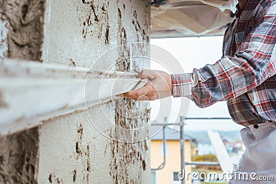 Plasterer smoothing plaster on a facade Stock Photo