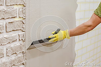 Plasterer smoothing plaster on wall Stock Photo