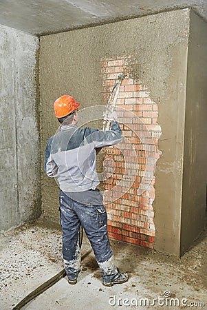 Plasterer spraying plaster on wall Stock Photo