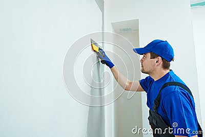 Refurbishment. Plasterer worker spackling a wall with putty Stock Photo