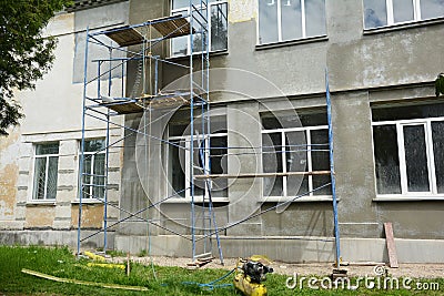 Plastering and painting the exterior house wall on scaffolds. The stucco process: applying brown stucco coat and finish top coat Stock Photo