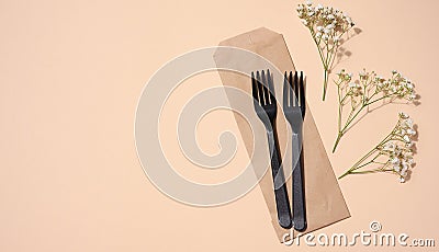 Plastic black forks on a beige background, disposable picnic items, top view Stock Photo