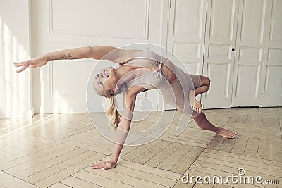 plastic blonde with a good stretch showing yoga asanas in a room by the window Stock Photo