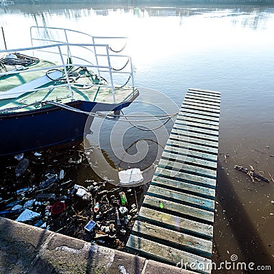 Plastic bottles, packages, trash in river near yacht. Illegal garbage dump, water pollution Stock Photo