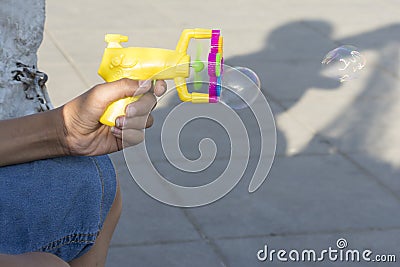 Plastic bubble makers gun in young teenage hand in outdoor area Stock Photo