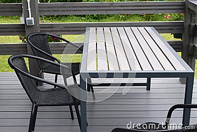 Plastic chairs and wooden table on WPC flooring terrace outdoors. Stock Photo