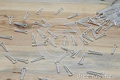 Plastic clips for fixing an electrical wire to the wall on a wooden background close up. Stock Photo