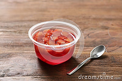 Plastic container with tasty jelly and spoon on table Stock Photo