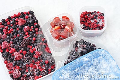 Plastic containers of frozen mixed berries in snow Stock Photo