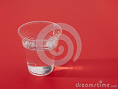 Plastic cup of fresh water over red,sidelit Stock Photo