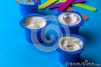 Plastic cup with tasty yogurt on blue table Stock Photo