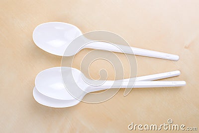 Plastic disposable white spoons on a wooden table Stock Photo
