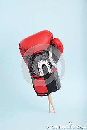 Plastic doll legs in heavy staggering boxing glove on minimal blue background Stock Photo