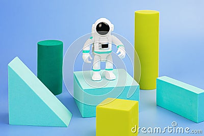 Plastic figurine of an astronaut in a spacesuit and geometric shapes on a blue background Stock Photo