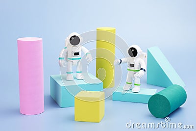 Plastic figurines of an astronauts in a spacesuit and geometric shapes on a blue background Stock Photo