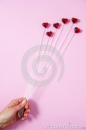 Plastic hearts on a pink background as a cluster of ballon, holding by a woman`s hand. Stock Photo