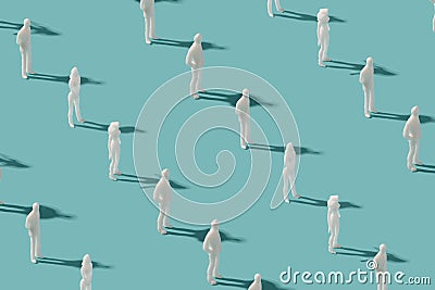 Plastic human figurines arranged on a pastel blue background. Stock Photo