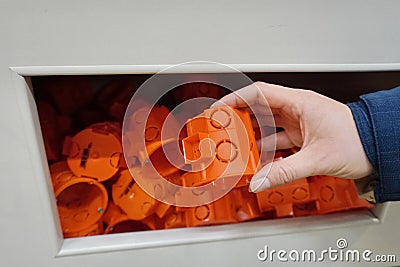 Plastic orange detail the power socket. AC power outlet device. A woman holds an orange plastic part of the outlet in her hand Stock Photo