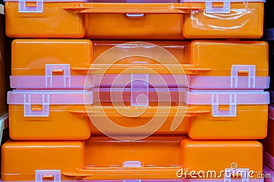 Plastic orange tool boxes on store shelves. Stack of organizers close-up Stock Photo