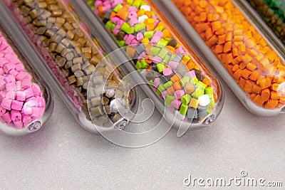 Plastic pellets .Polymeric dye in test tubes on gray background. Stock Photo