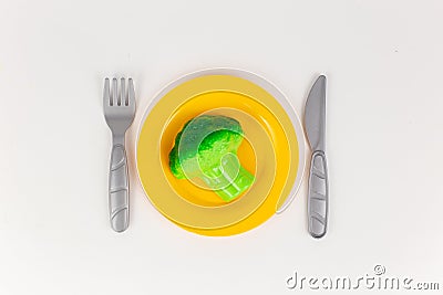 plastic plate with a knife and fork with broccoli on a white background Stock Photo