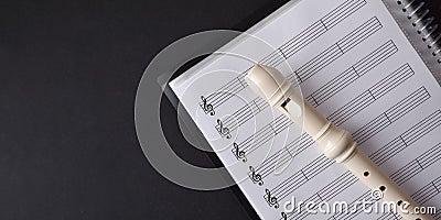 Plastic recorder on sheet music folder on a black table Stock Photo