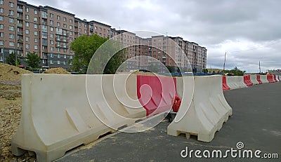 Plastic red and white heavy duty water filled road traffic barrier. Construction of freeway near multi-story residential buildings Stock Photo