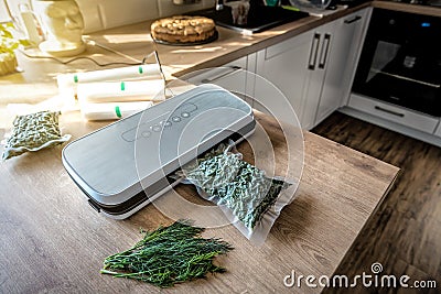 Plastic sealing machine. Vacuum packaging of fresh dill Stock Photo