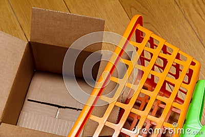 Plastic shopping basket on the floor and an open cardboard box Stock Photo