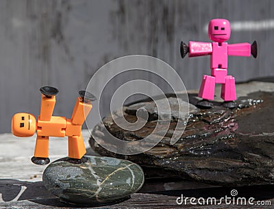 Plastic stick figures posed on wet rocks. Stock Photo