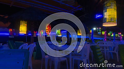 Plastic tables in a disco bar with blue lights near the beach Stock Photo