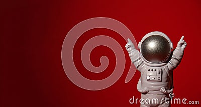 Plastic toy astronaut on colorful red background Copy space. Concept of out of earth travel, private spaceman commercial Stock Photo