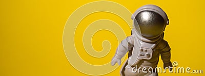 Plastic toy astronaut on colorful yellow background Copy space. Concept of out of earth travel, private spaceman Stock Photo