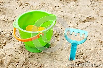 Plastic toy bucket and a blue sand rake on the sand Stock Photo