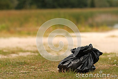 Black packet with garbage on countryside lake Stock Photo