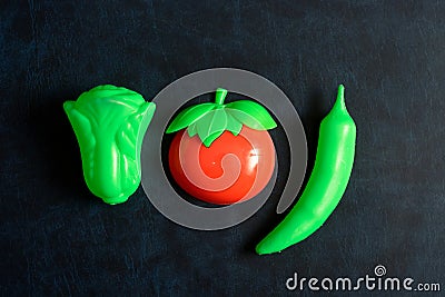 Plastic vegetable collection set of tomato, chili and lettuce on isolated dark background Stock Photo