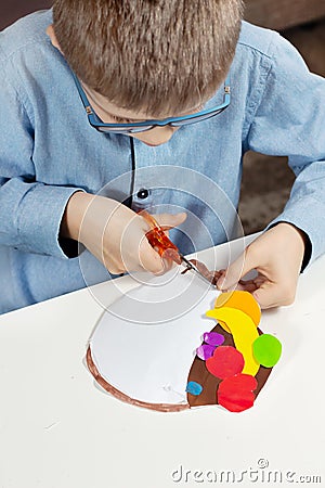 Plastic work done by a child. The boy is cutting out with paper scissors. Stock Photo