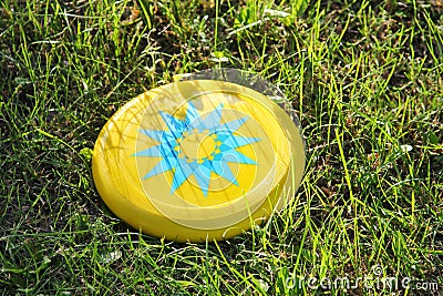 Plastic frisbee flying disc lying in the grass in the park. Children`s toy for active outdoor games. Stock Photo