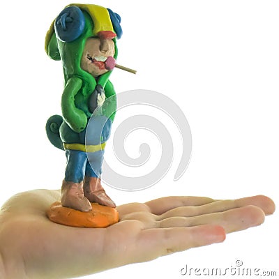 Plasticine boy with candy in his mouth, on the hand of a child. Stock Photo