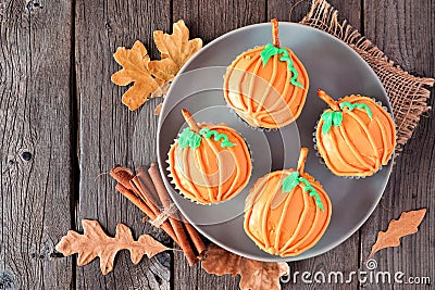 Plate of autumn pumpkin cupcakes on a rustic wood background Stock Photo