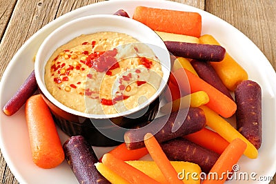 Plate of baby rainbow carrots with hummus close up Stock Photo