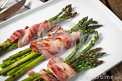 Cooked asparagus with wrapped bacon on plate Stock Photo