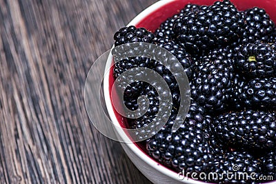 Plate with blackberries. Blackberries on wooden background. Sweet, ripe blackberries in bowl Stock Photo
