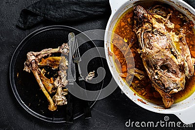 A plate of chicken bones and a chicken skeleton in a baking dish. Leftovers from dinner. Black background. Top view Stock Photo