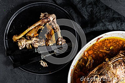 A plate of chicken bones and a chicken skeleton in a baking dish. Leftovers from dinner. Black background. Top view Stock Photo