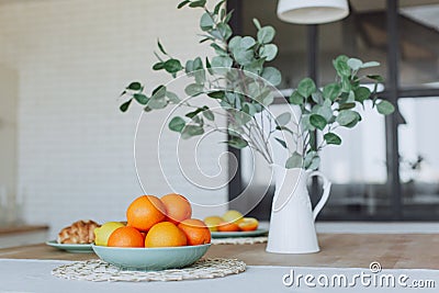 Plate with citrus fruits standing on wooden table in the kitchen Stock Photo