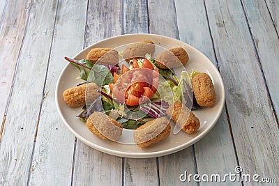 plate of croquettes stuffed with fried chicken with bÃ©chamel sauce with sprouts and tomato salad Stock Photo