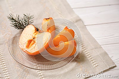 Plate with cut ripe persimmon on white wooden table Stock Photo