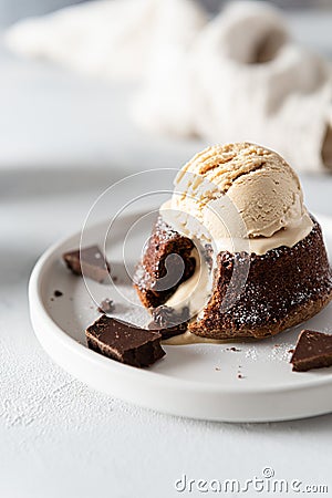 Plate of delicious french fondant with hot chocolate and vanilla ice cream scoop ont the top on the plate. Lava cake recipe, menu Stock Photo