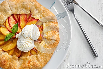 Plate with delicious peach galette and ice-cream on white wooden table Stock Photo